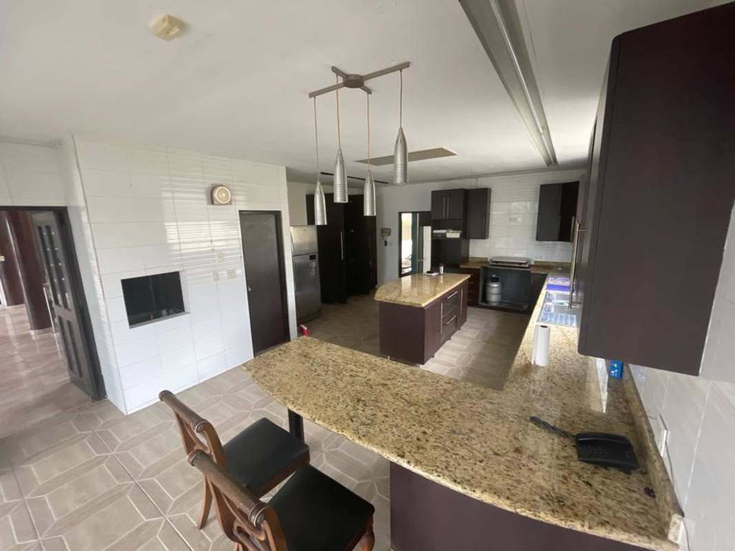 Modern kitchen with island, granite countertops, pendant lighting in luxury home Dos Mares Panama City