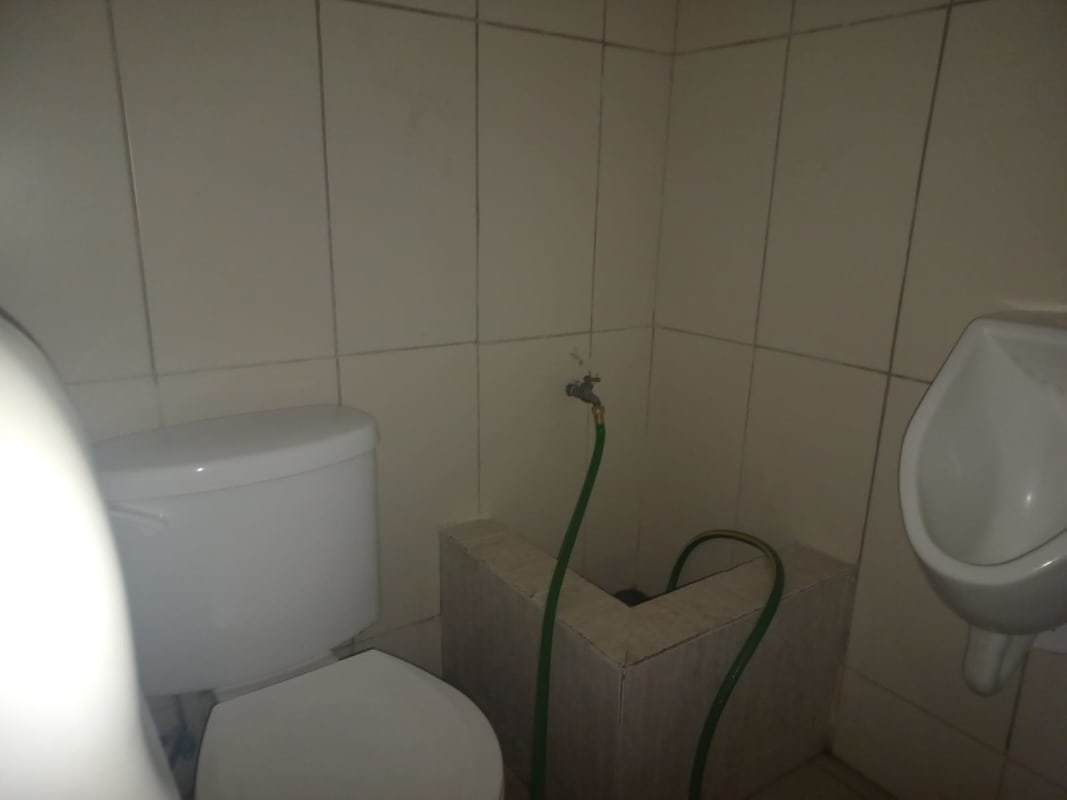 Men's restroom with urinal, toilet and tiled walls at Plaza Business Gallery Brisas del Golf