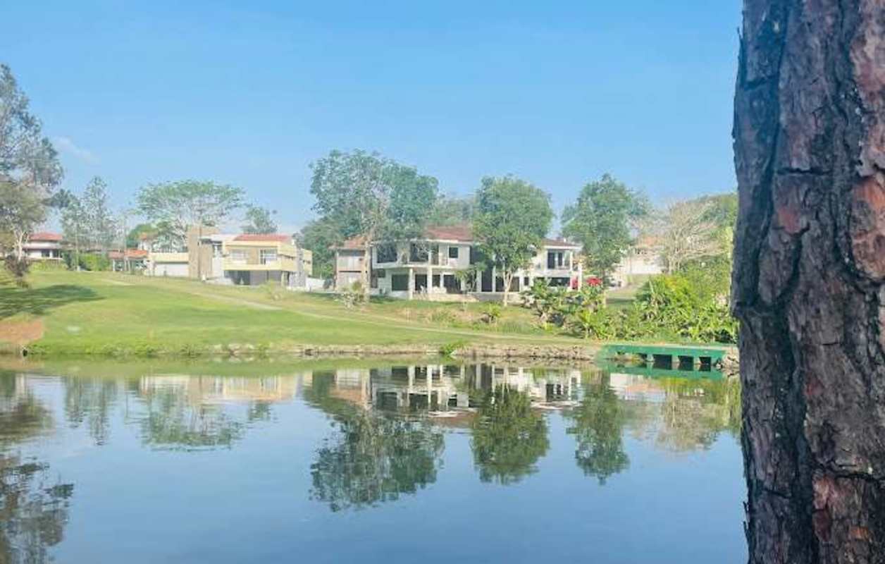 Lakeside view with modern Mediterranean homes, lush trees, and reflections at Club de Golf de Panamá