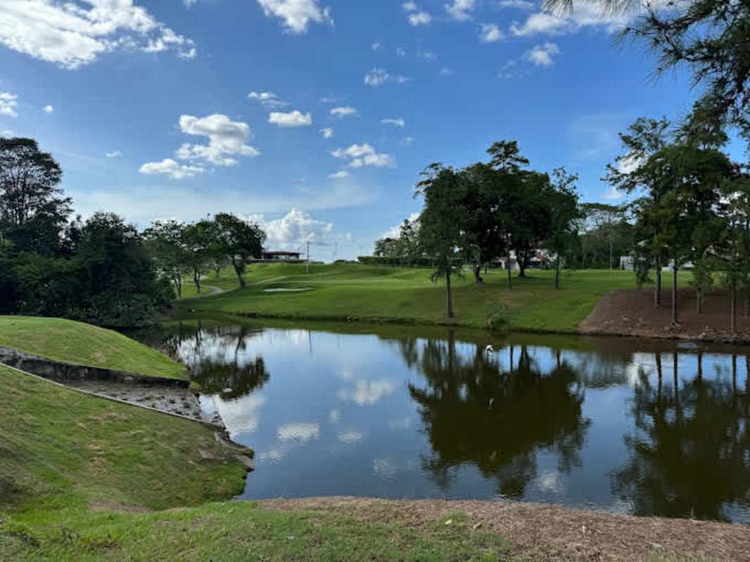 Peaceful golf fairways with pond, lush lawn, trees, reflecting sky at Club de Golf de Panamá