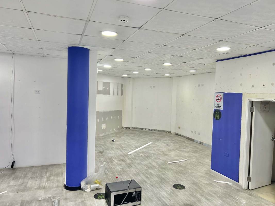Empty retail commercial interior with gray flooring blue pillar white walls drop ceiling recessed lights in San Francisco Panama