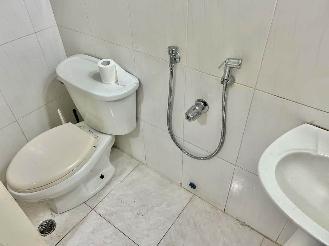 Minimalist bathroom with white ceramic tiles toilet hand bidet sprayer in commercial rental Panama Calle 50