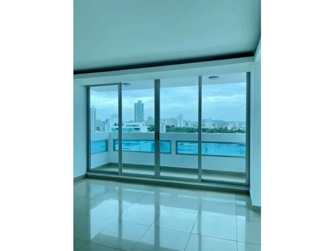 Modern living room with floor-to-ceiling windows and balcony access overlooking Panama City skyline
