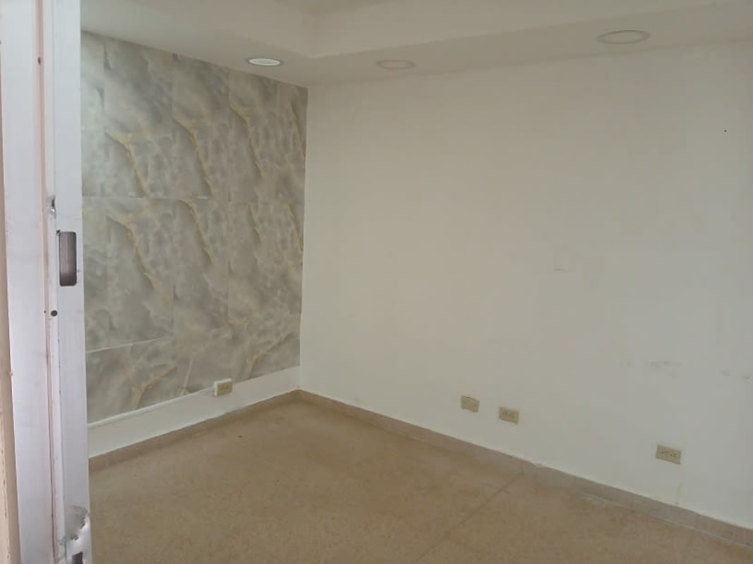 Empty office with marble accent wall, recessed lights, beige tiled floor PH Panama Business Center Panama