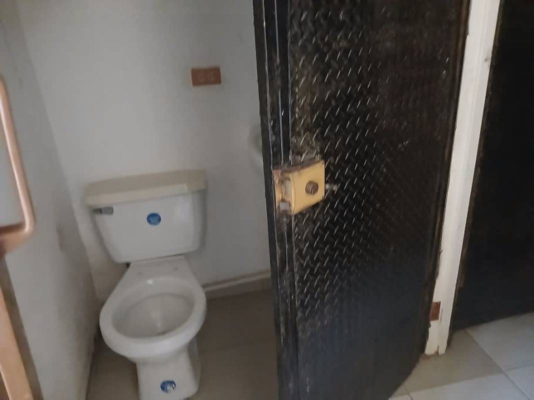 Basic restroom with white toilet and black door in Obarrio Business Plaza Panama