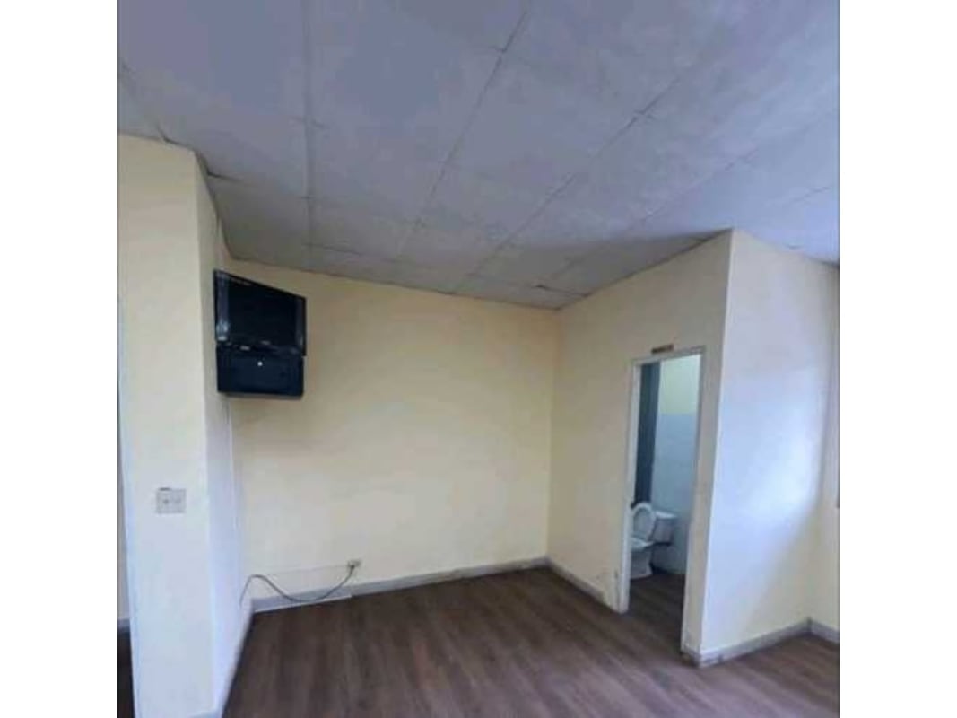 Interior with wood floors, mounted TV, cream walls, access to bathroom inside warehouse building Panama