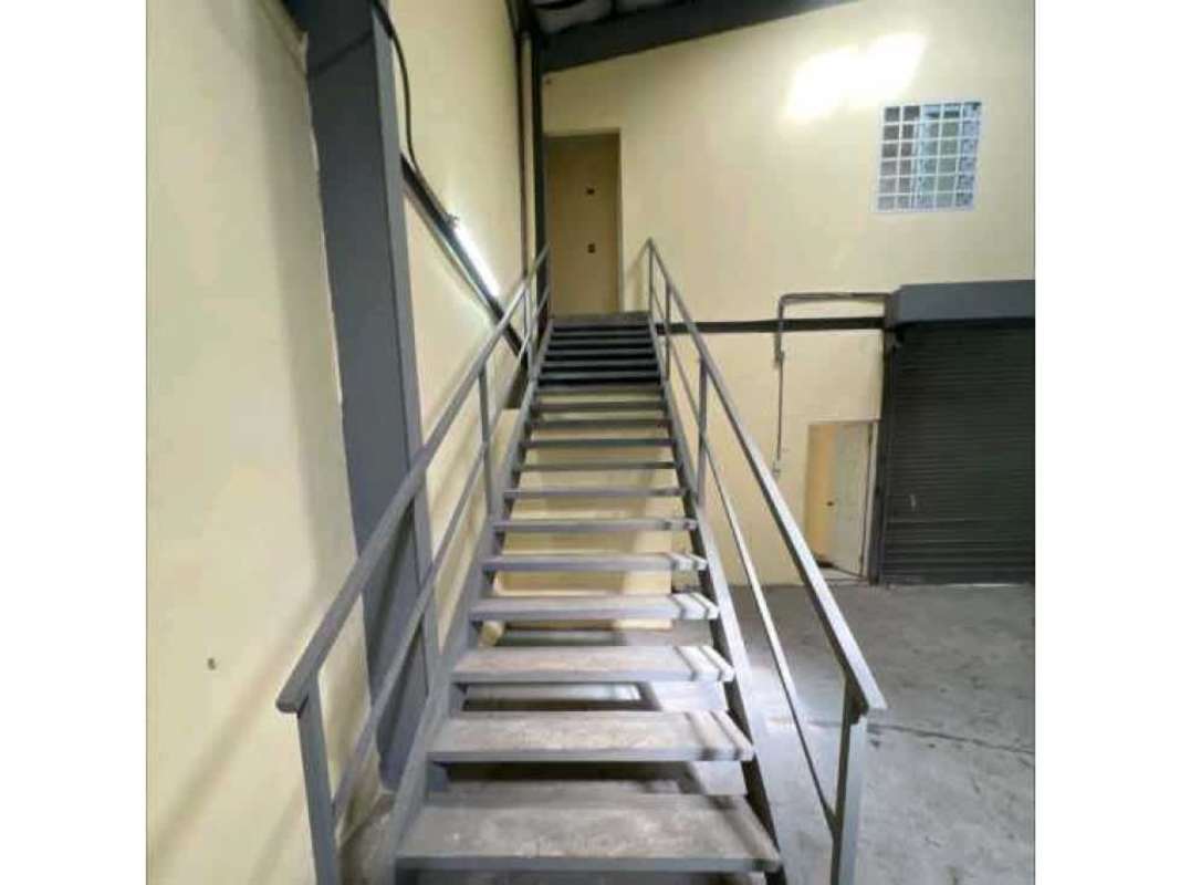 Warehouse with metal stairs to mezzanine, exposed ceiling beams, glass block window in Panama City