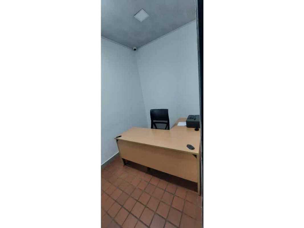 Small minimalist office space with wooden desk, black chair, tiled floor inside Plaza Triumph Panama