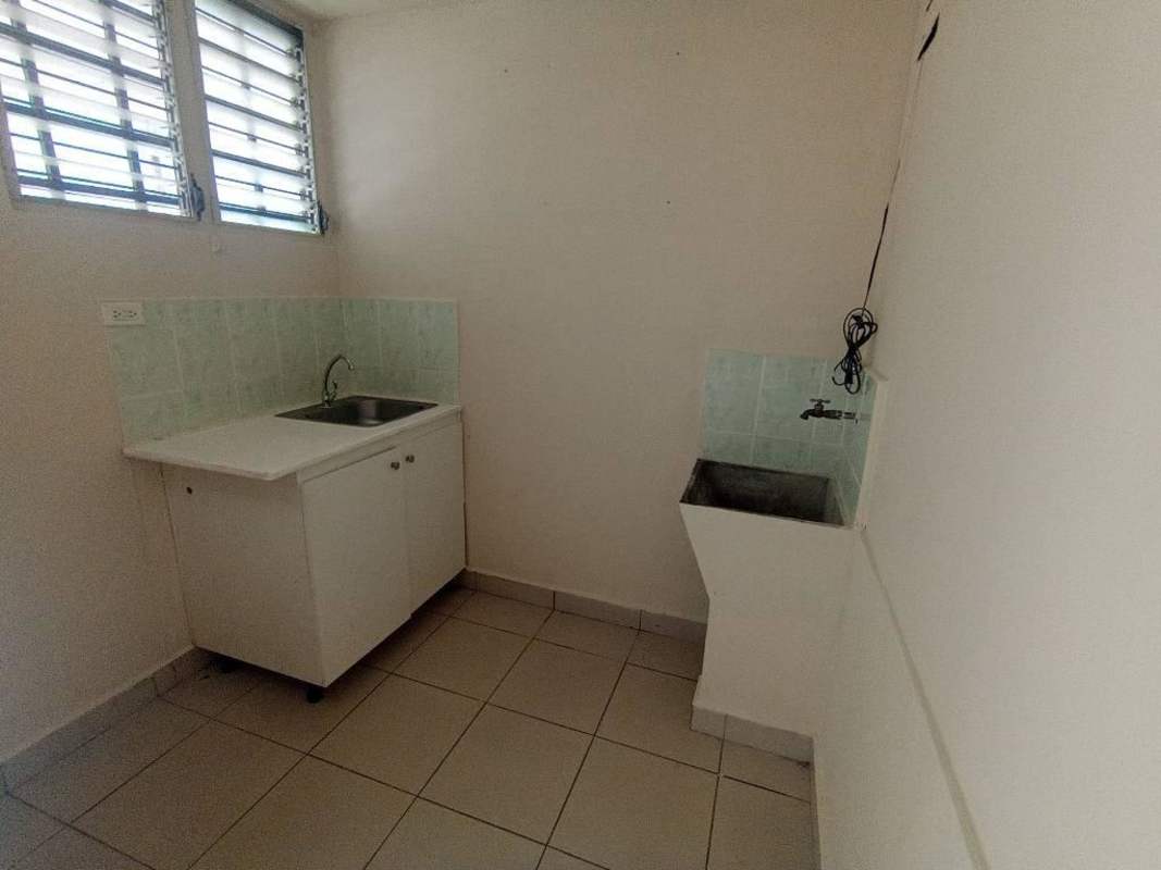 White laundry area with utility sink, cabinet storage, louver windows in apartment Rio Abajo Panama