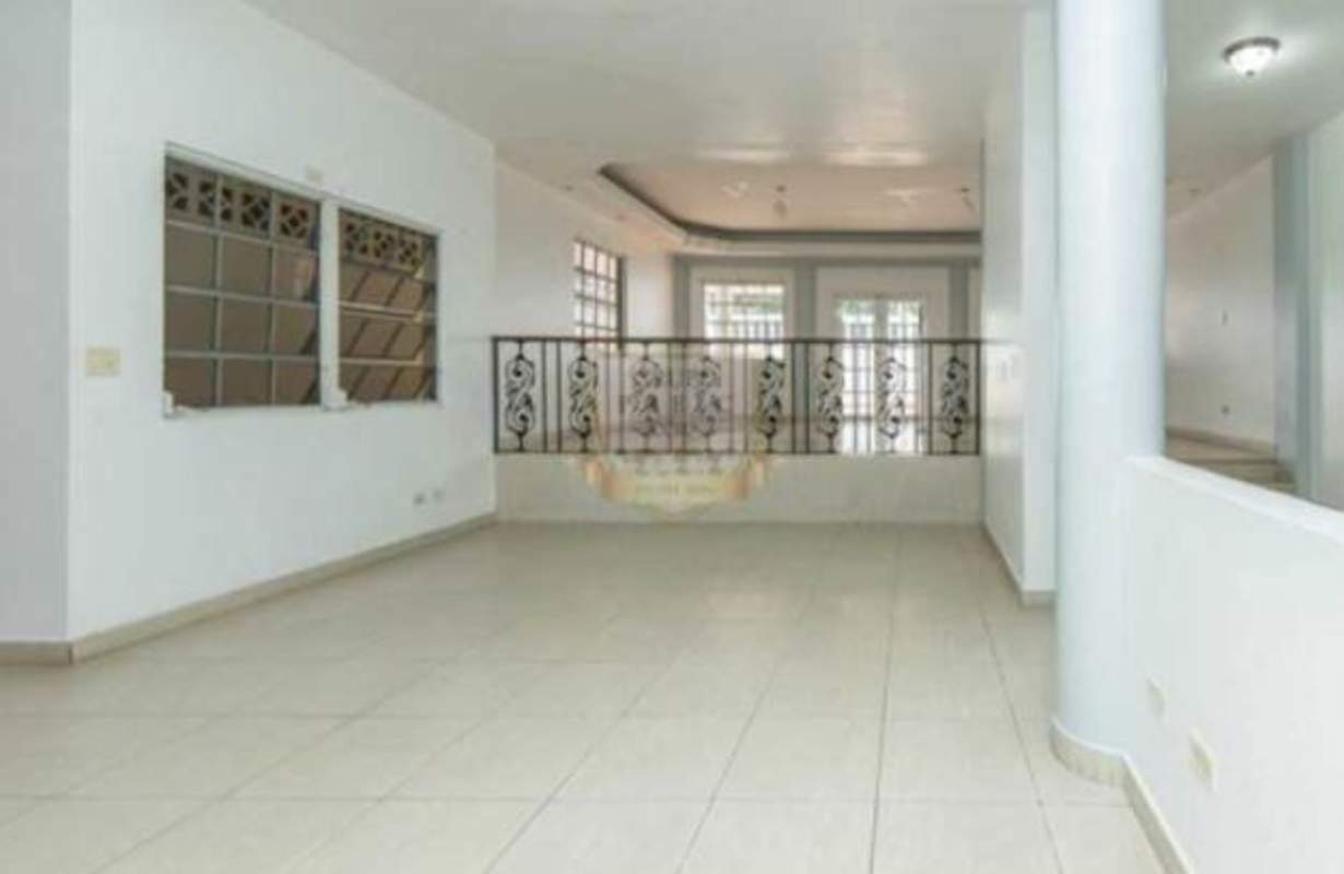 Large covered terrace with pillars and tile floor overlooking backyard in Villa de las Fuentes Panama