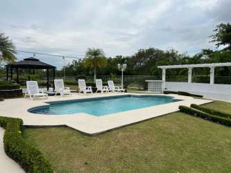 Poolside area with lounge chairs, pergola, landscaping and gazebo in Coronado beach house