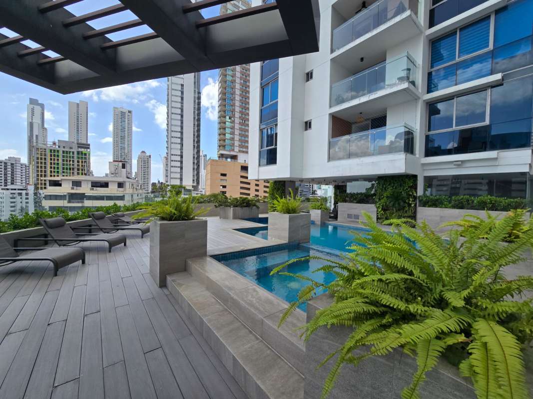 Rooftop deck with lounge chairs, pergola overlooking water and skyscrapers at PH Vita Panama City