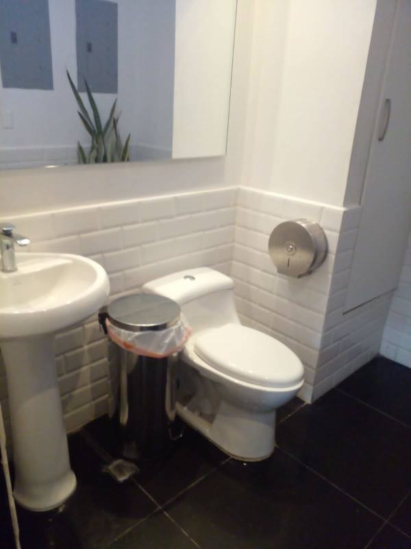 Minimalist bathroom with pedestal sink, white subway tiles, wall mirror in commercial space in Plaza 74 Panama City