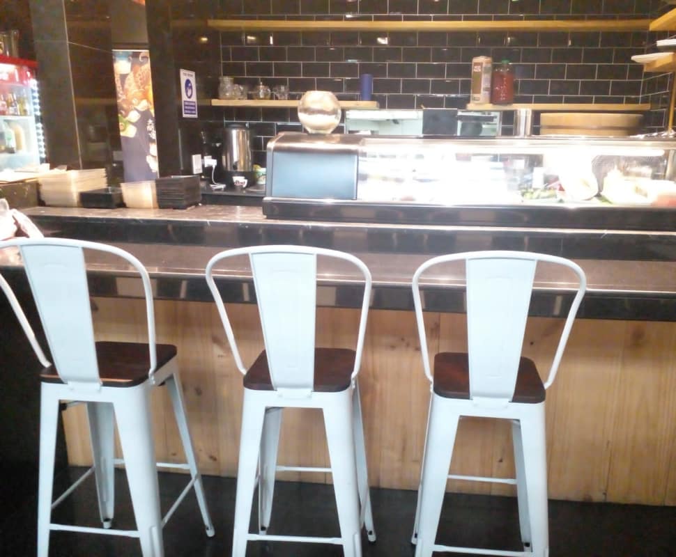 Commercial bar with glass display, black tiles, wood panel base in restaurant space Plaza 74 Panama City