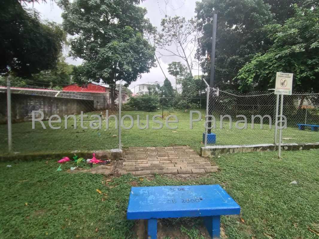 Sports court surrounded by green lawns, trees and a shaded gazebo in Carrasquilla Panama