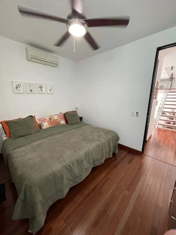 Bedroom with work desk, lounge area, wood flooring and natural light in Altos del Golf house