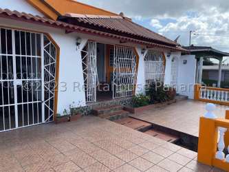 House facade with tiled porch, iron security bars on windows and front steps in La Chorrera Panama