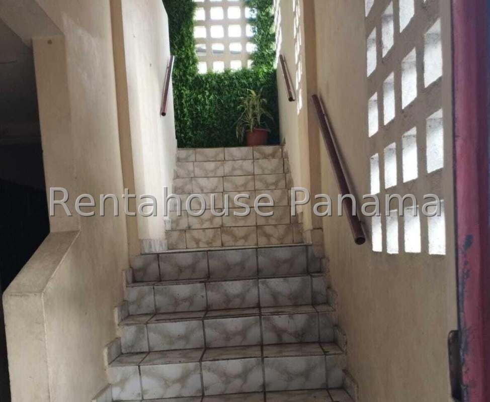 Traditional kitchen with brown cabinets, gas stove, refrigerator, microwave, and large frosted windows Parque Lefevre Panama