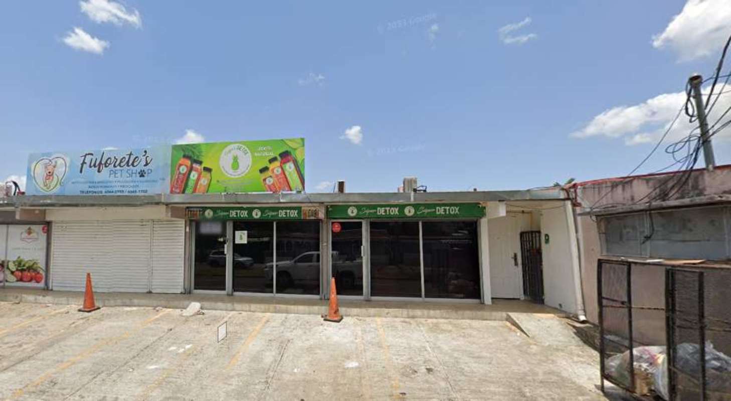Glass-front single-story commercial plaza with parking area on Vía Cincuentenario Panama City