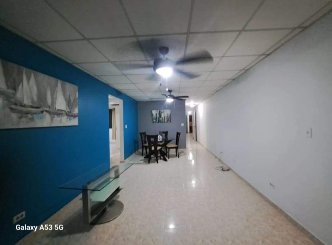 Open plan living dining room with tile floor, accent wall and ceiling fans in Betania Panama