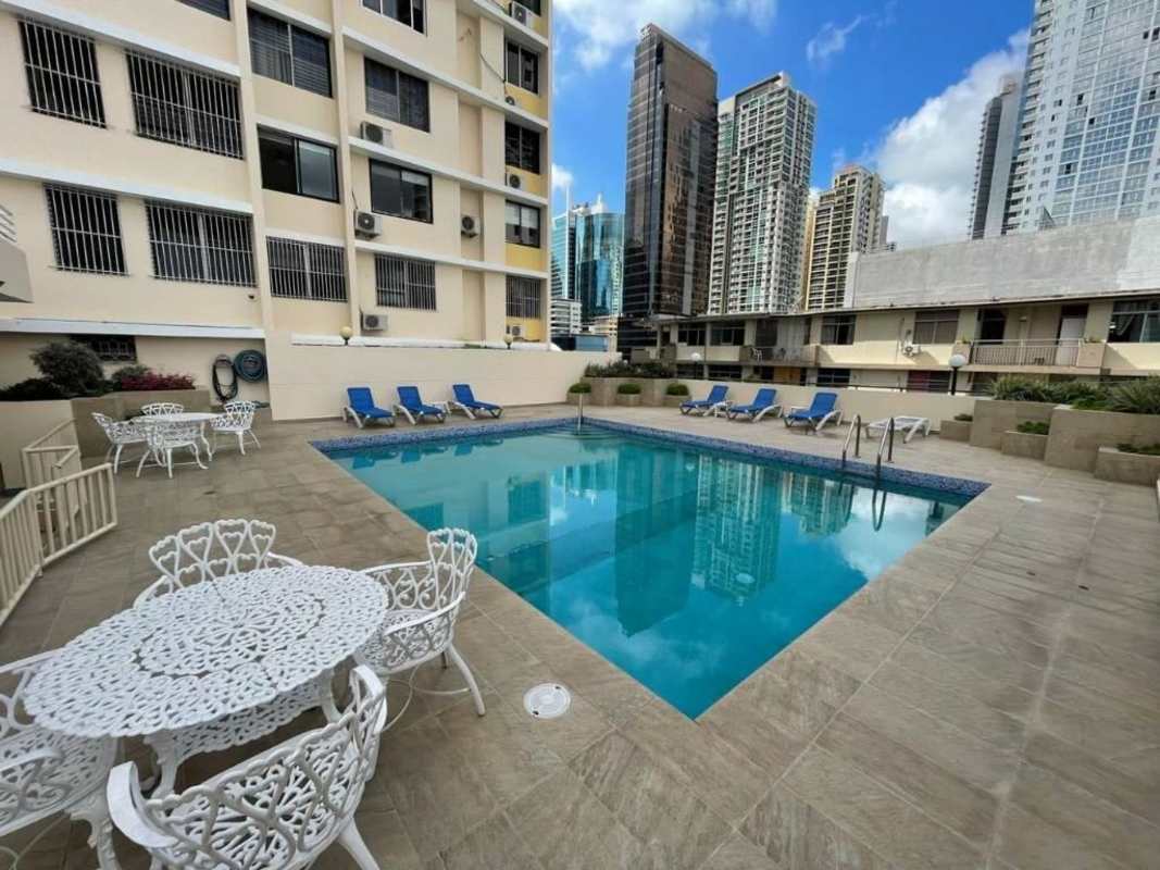 Outdoor pool with lounge chairs and city skyline at PH Mónaco Panama City