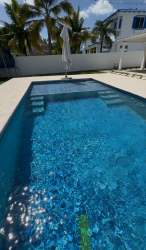 Blue pool with white fence palm trees patio furniture Playa Blanca beach house Panama