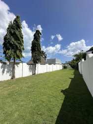 Expansive grassy fenced backyard with tall trees Playa Blanca beach house Panama