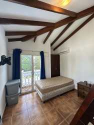 Rustic bedroom with exposed beams, tile floor, balcony access Playa Blanca Panama