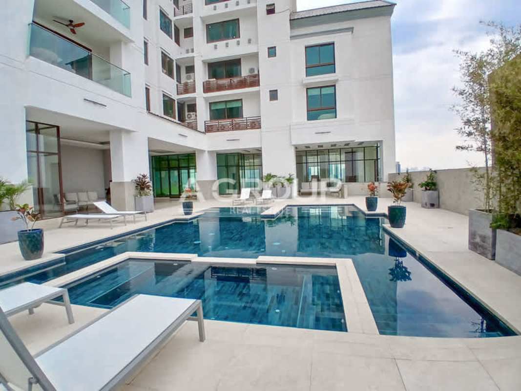 Infinity pool with sun loungers and modern luxury condo facade in The Colonial Panama