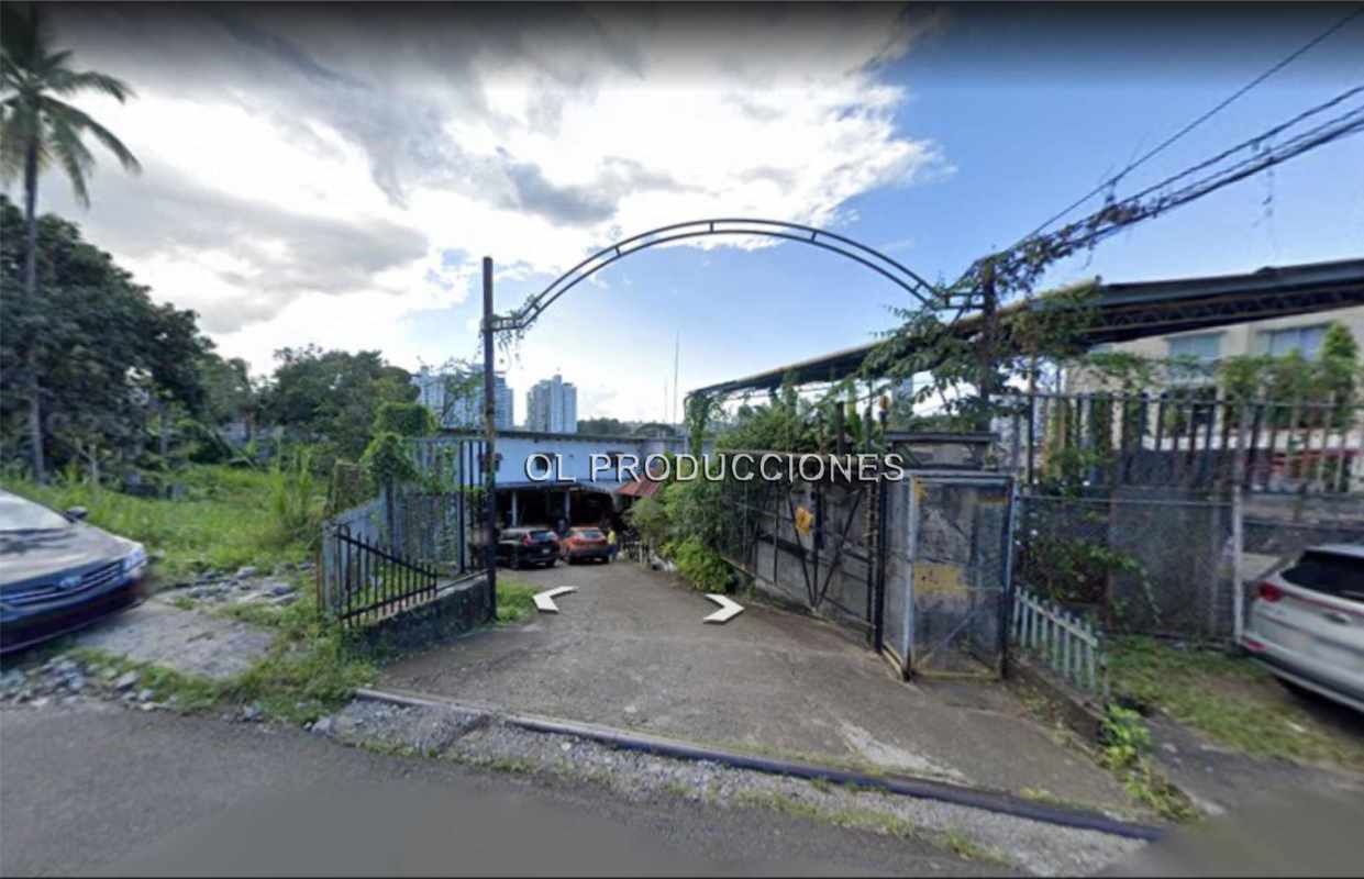 Street level view fenced development site with cars and paved frontage