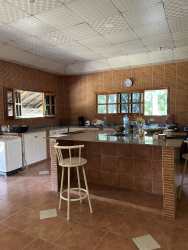 Rustic kitchen with tiled counters, white cabinetry and garden views in Panama countryside house