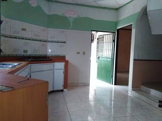 Kitchen with tiled walls, green door, archway, corner countertop in duplex for rent in Chitré Panama