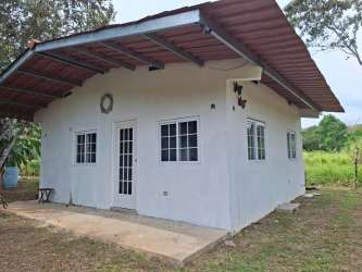 Small white countryside house with red roof surrounded by trees and natural garden in Las Uvas Panama