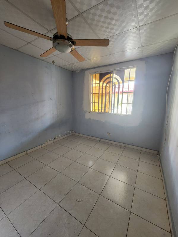 Bedroom with ceiling fan light blue walls metal window Bars tiled floor Panama