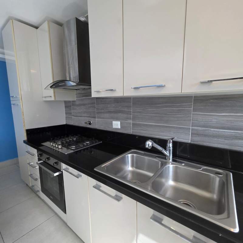 Modern kitchen with built-in appliances and adjacent laundry area in PH Park City Obarrio Panama City