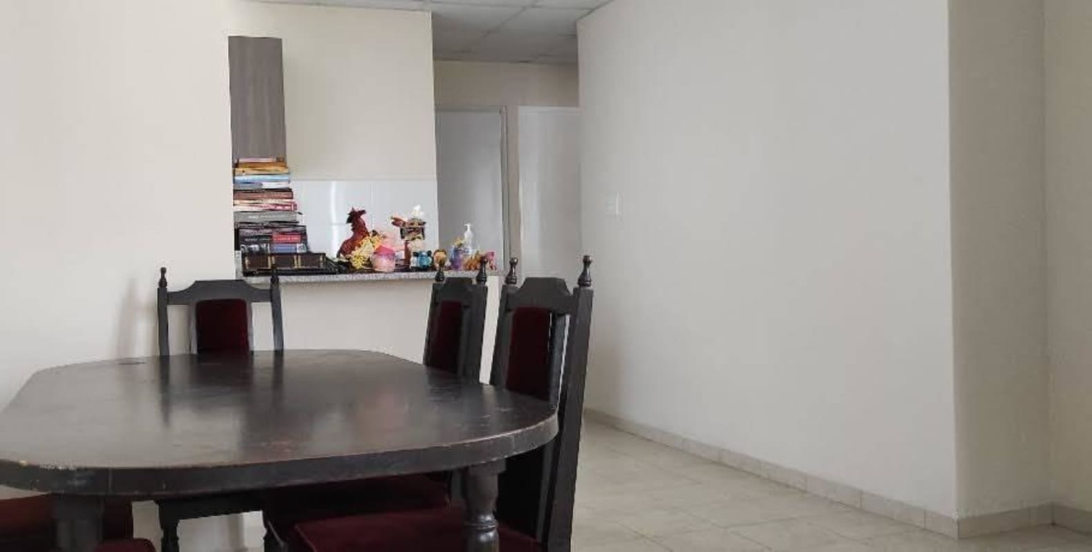 Open dining and kitchen area with dark wood table, minimalist decor, tile floors in Pacora Panama