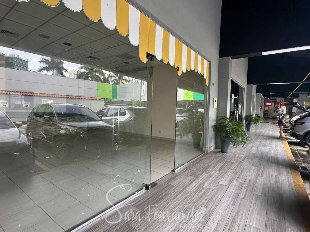 Modern commercial plaza exterior with glass storefront, striped awning, walkway, parking in Costa del Este Panama