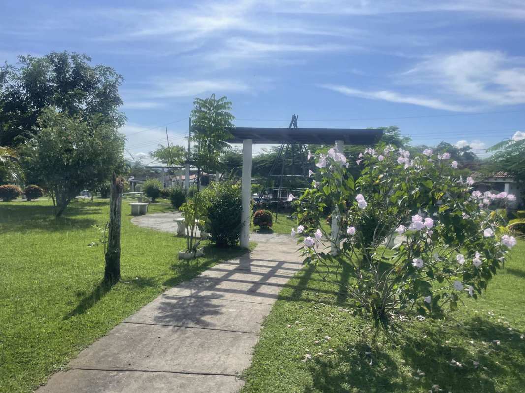 Sunny garden common area with lawn, pergola and flowers at PH Las Cumbres Panama City