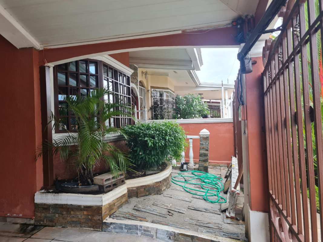 Traditional house entrance with bay window, iron gate, garden in San Antonio Panama