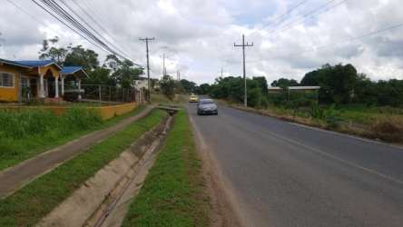 Street view fenced commercial land corner lot with house and utility poles La Chorrera