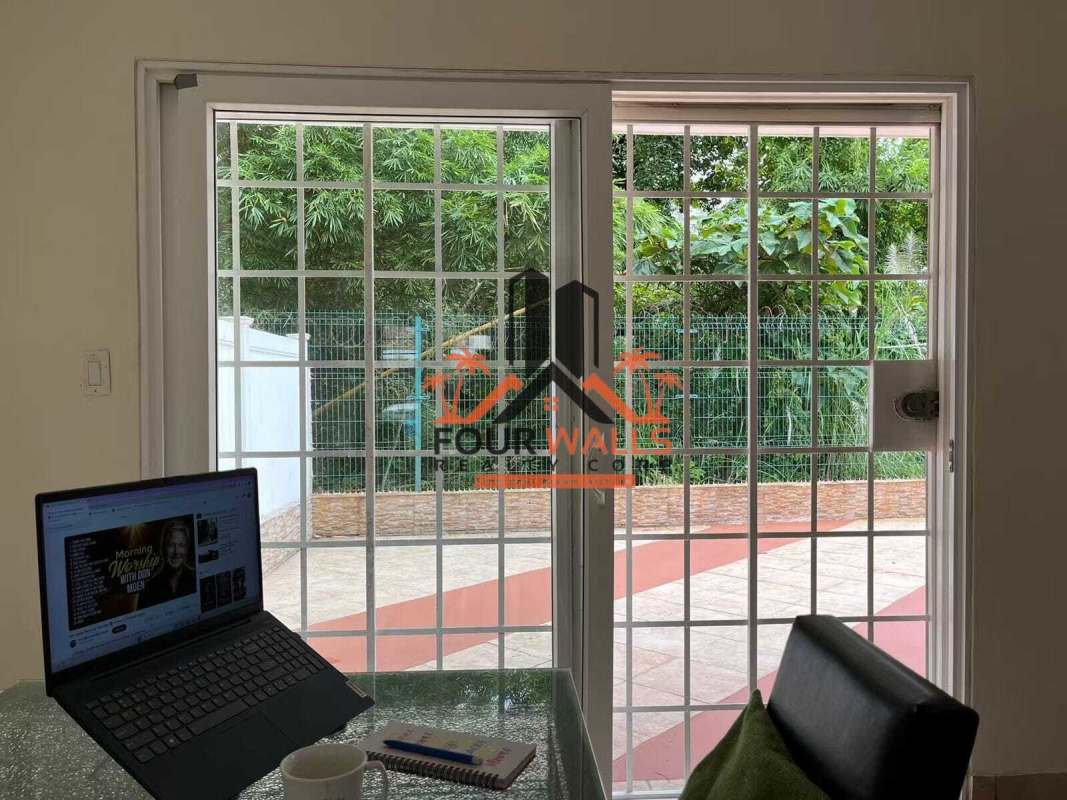Bedroom with dual single beds, ceiling fan, barred window with green view in PH Everest Panama