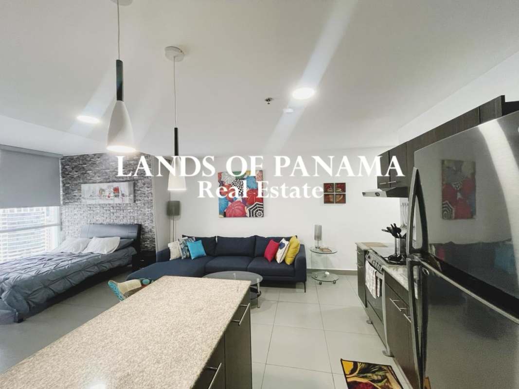 Bedroom zone of furnished apartment with large window ocean and city views PH Colores de Bella Vista