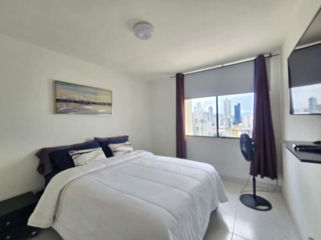 Bedroom with window overlooking Panama City skyline at PH Obarrio Suites Obarrio