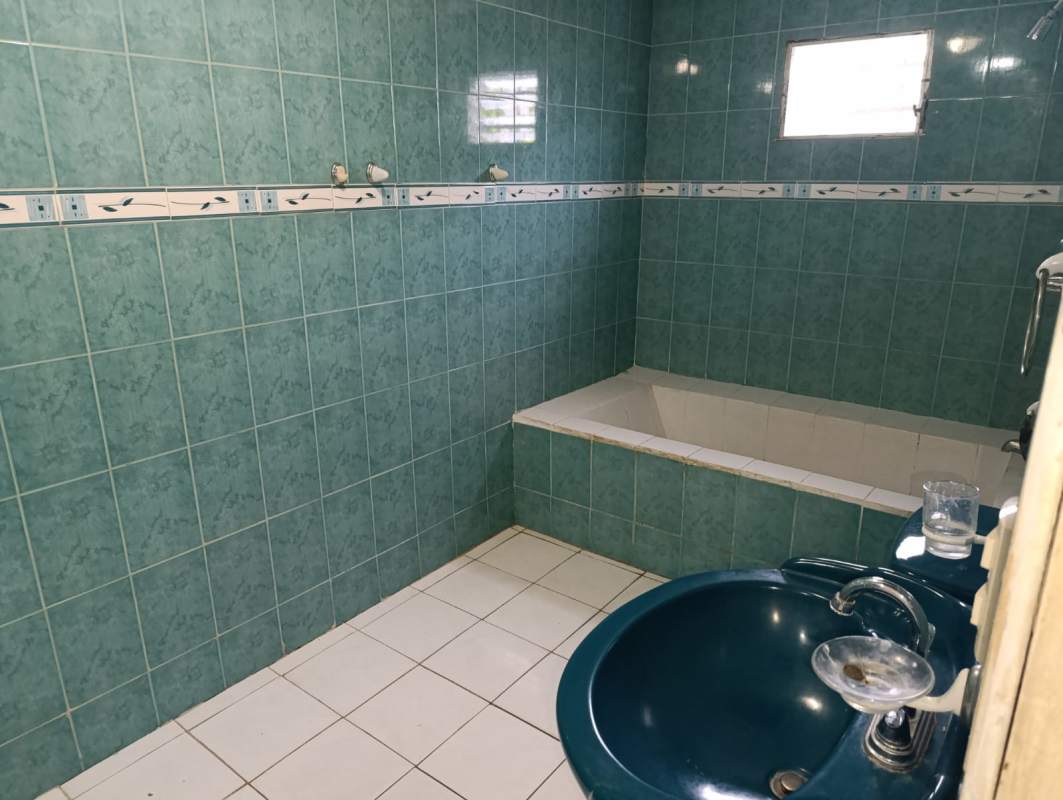 Traditional bathroom with teal tiles, bathtub, pedestal sink in Villas de Don Bosco house Panama City