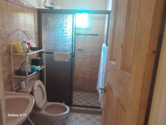Bathroom with glass shower, beige tiles, and toilet in Pocrí Penonomé Panama