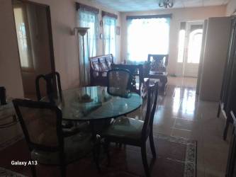 Dining room with glass table, sofa set, large windows in house Penonomé Panama