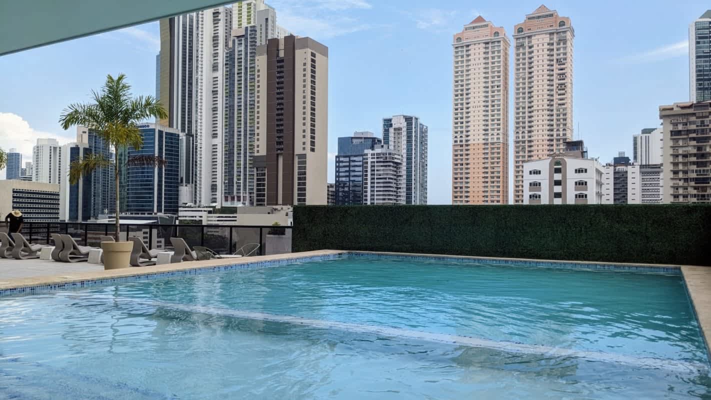 Rooftop swimming pool with sun chairs overlooking skyline at PH Costa Pacifica