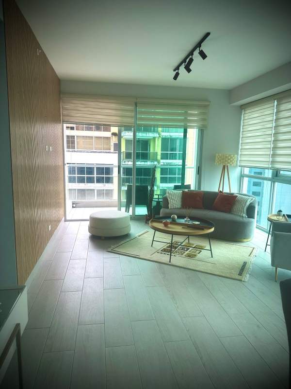 Living area with large windows, wood accent wall, stylish decor PH Urbana Obarrio Panama