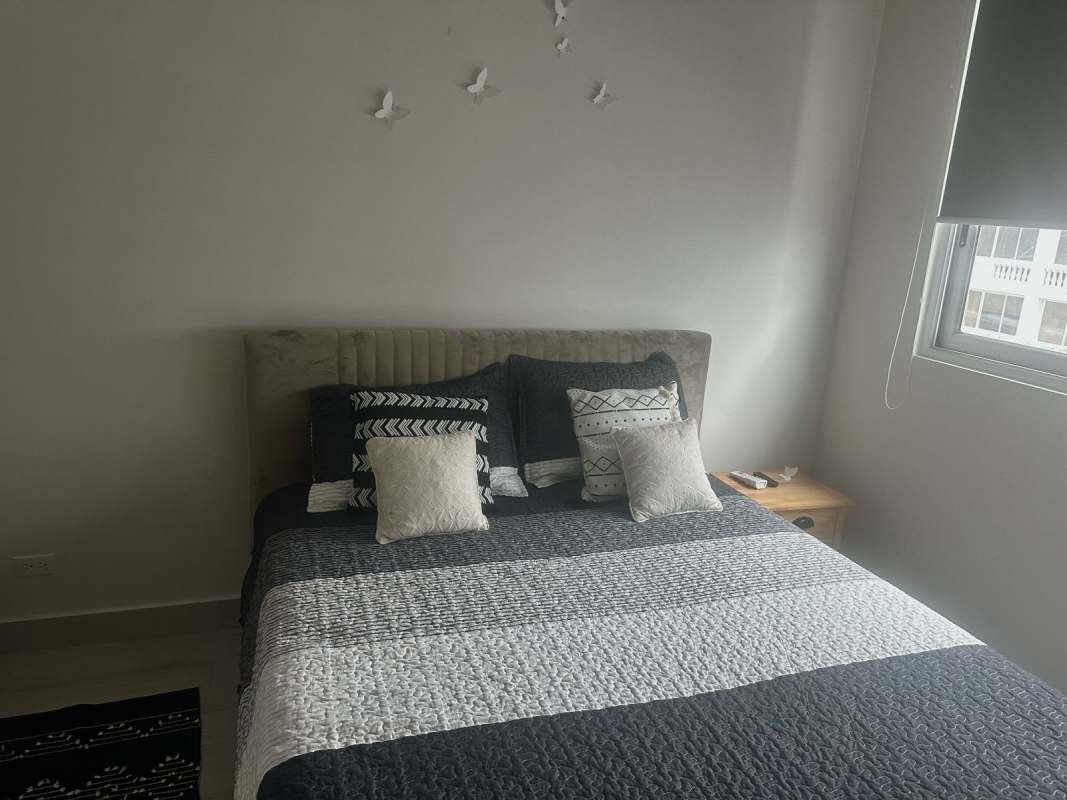 Modern bedroom with striped bedding, headboard, city view PH Urbana Panama City