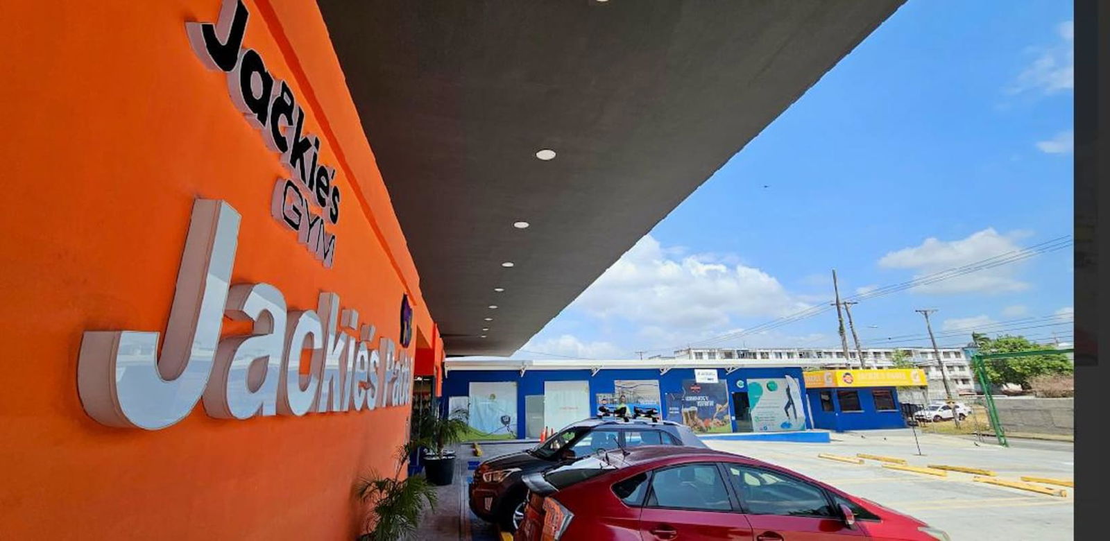 Parking lot with orange facade and blue storefronts Jackie's Padel Business Center Panama